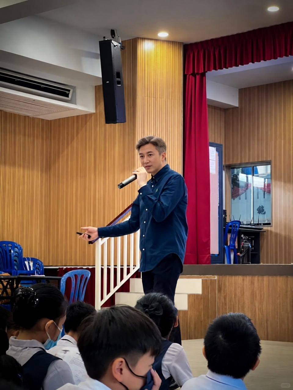 講師在禮堂舞台上，拿著麥克風為同學們講解反詐騙知識