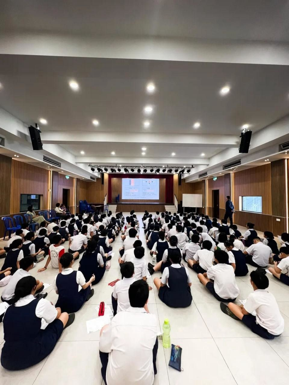 禮堂裡同學們穿著制服席地而坐，認真聆聽反詐騙宣導